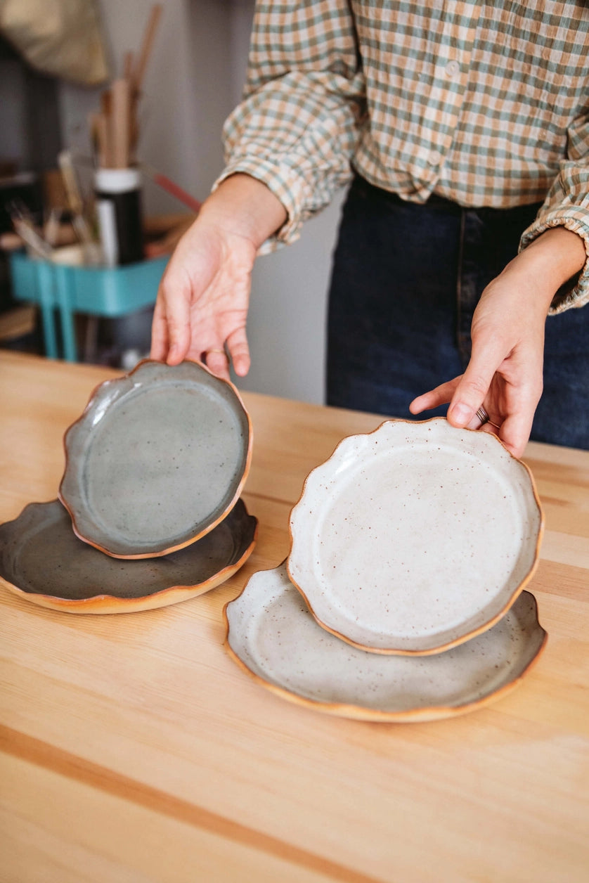 Assiette en grès de deux tailles différentes et de deux couleurs différentes tenues par une personne.