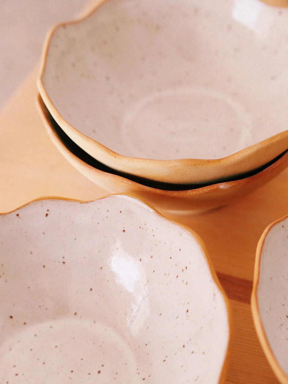 Des bols en grès de couleur blanc cassé posés sur une table.