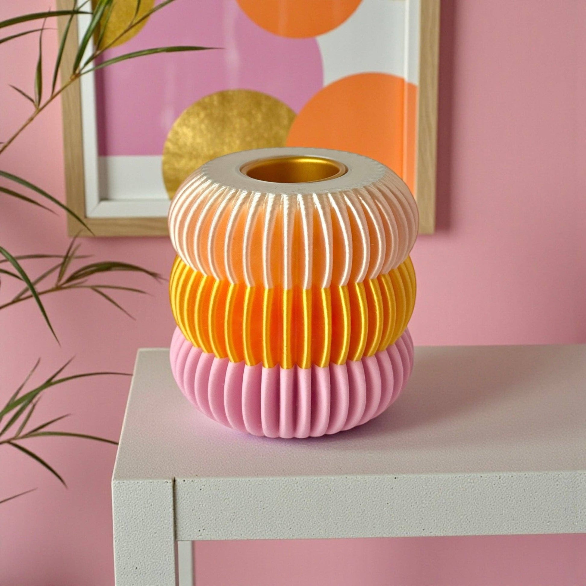 Bougeoir design nervuré aux tons rose, orange et blanc, posé sur une table blanche dans un univers déco pop et lumineux.