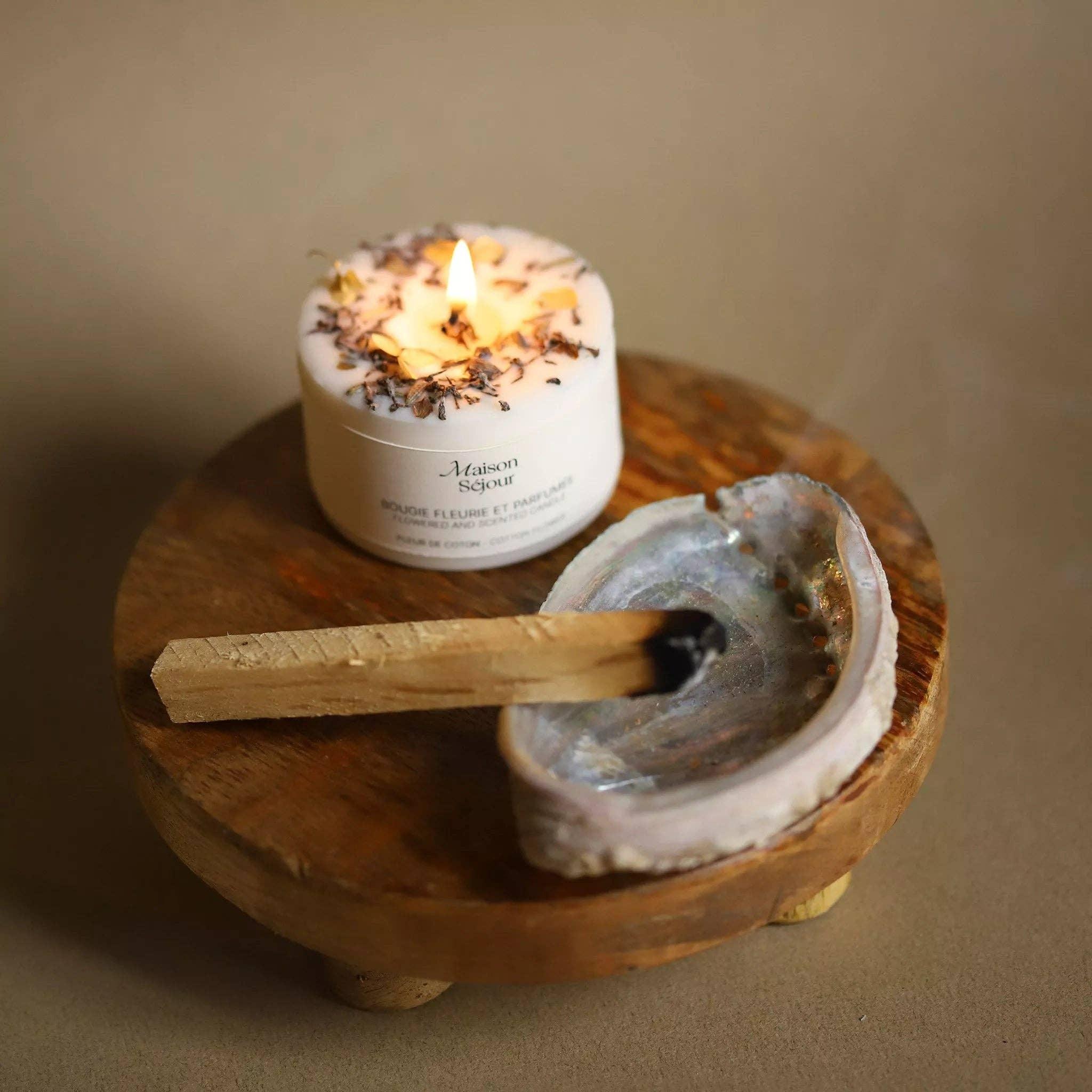 Bougie parfumée artisanale allumée sur support en bois, ambiance chaleureuse