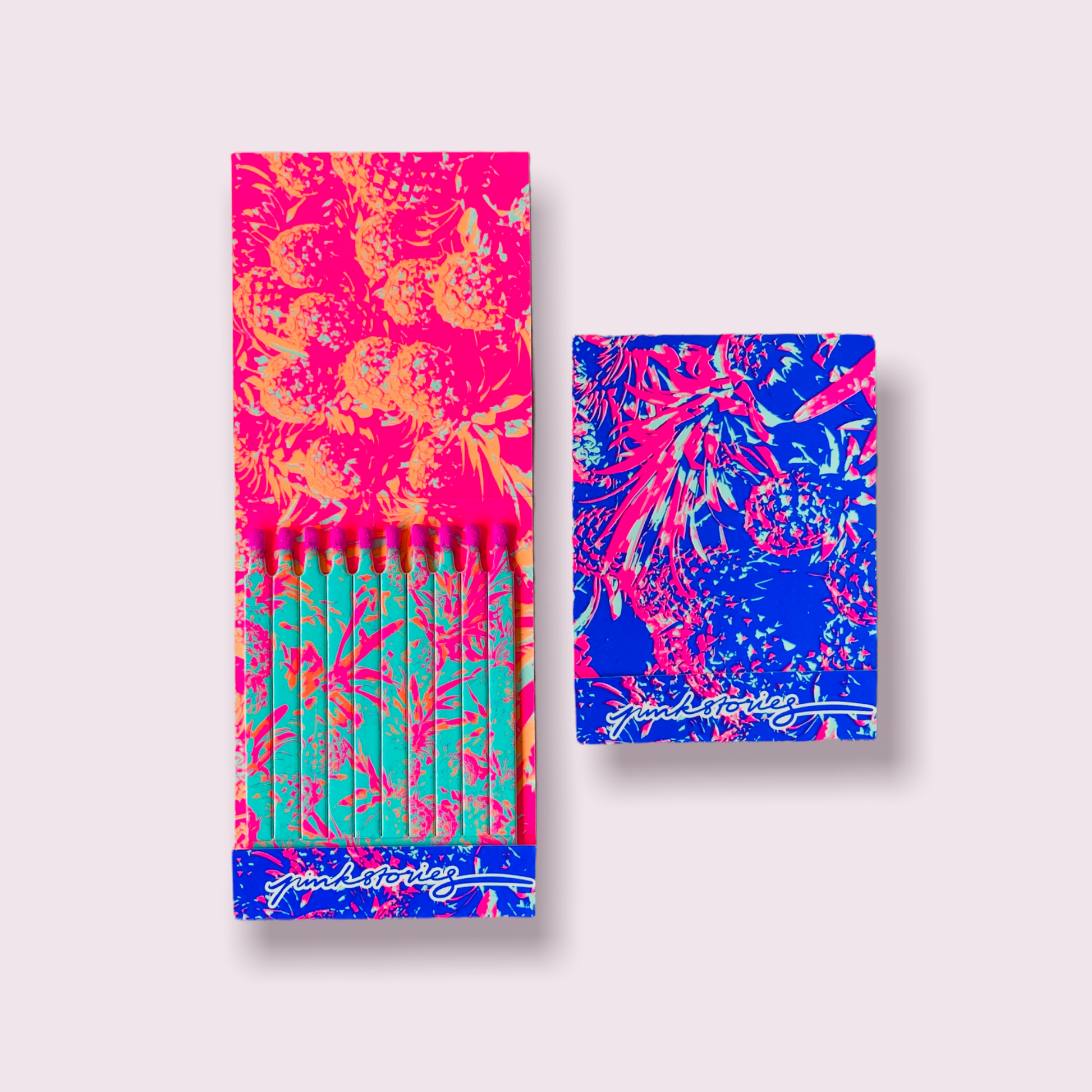 Carnet d’allumettes ouvert avec intérieur imprimé et allumettes assorties, accompagné de son étui au motif tropical rose et bleu pour un rendu très pop.