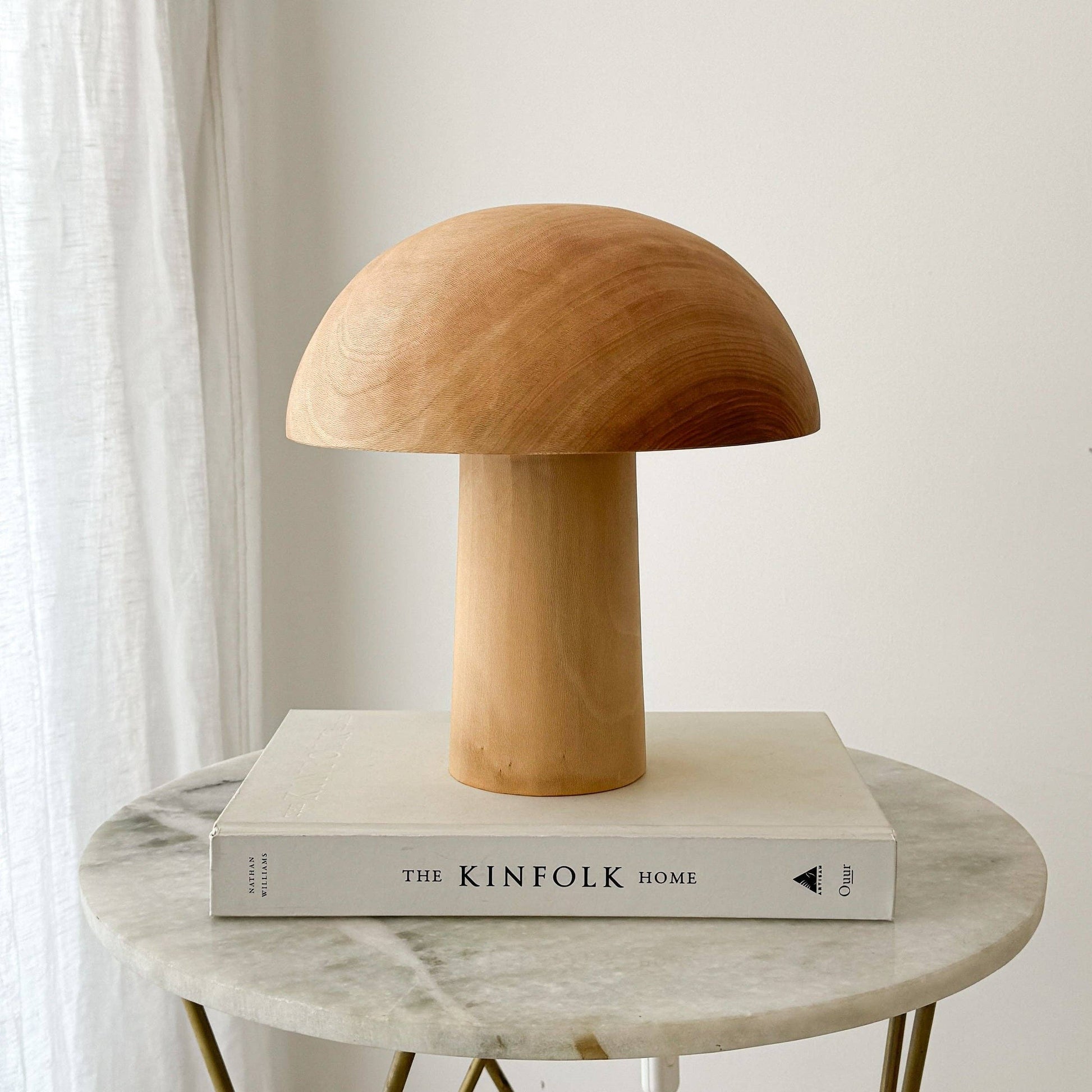 Une lampe en bois éteinte, en forme de champignon posée sur un livre.