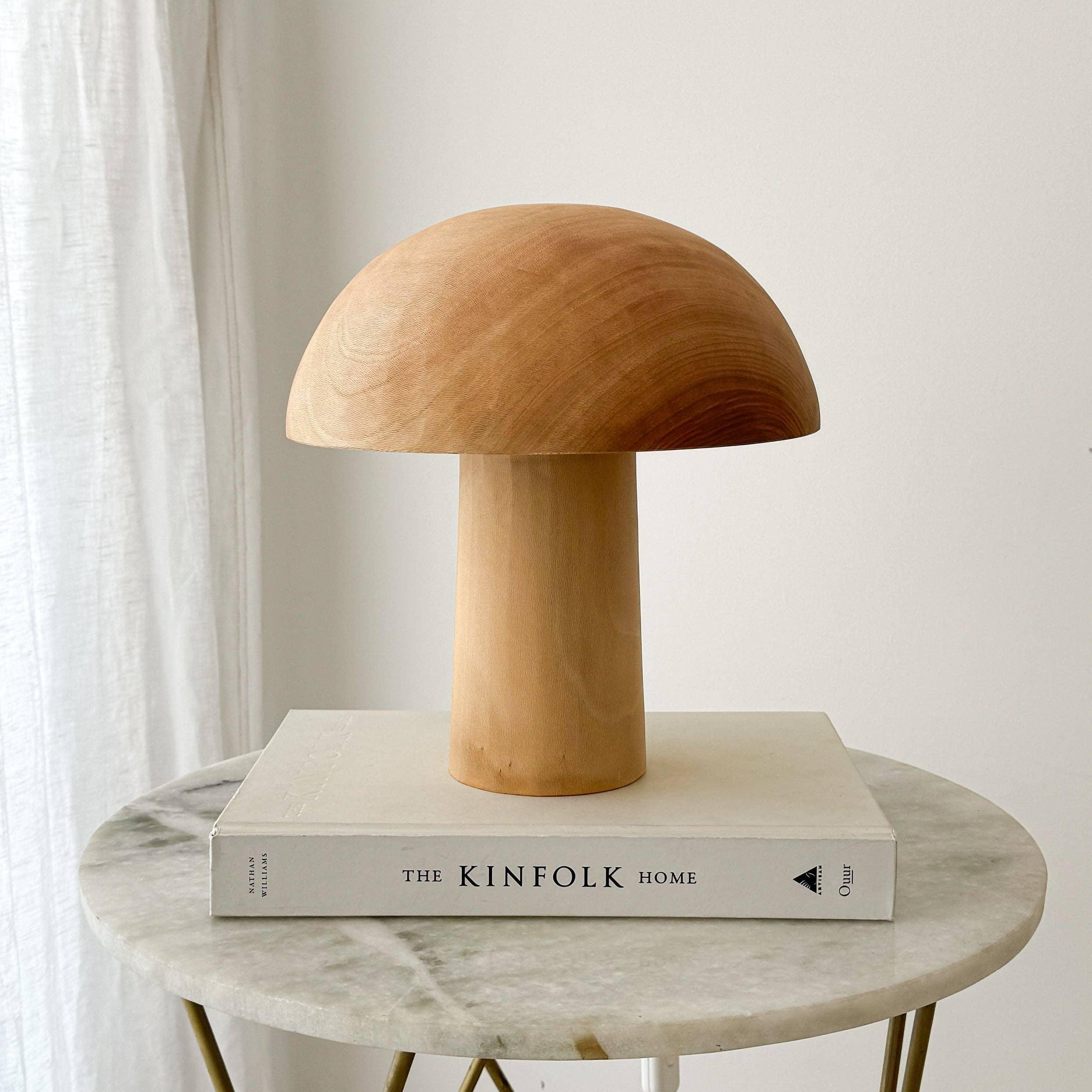 Une lampe en bois éteinte, en forme de champignon posée sur un livre.