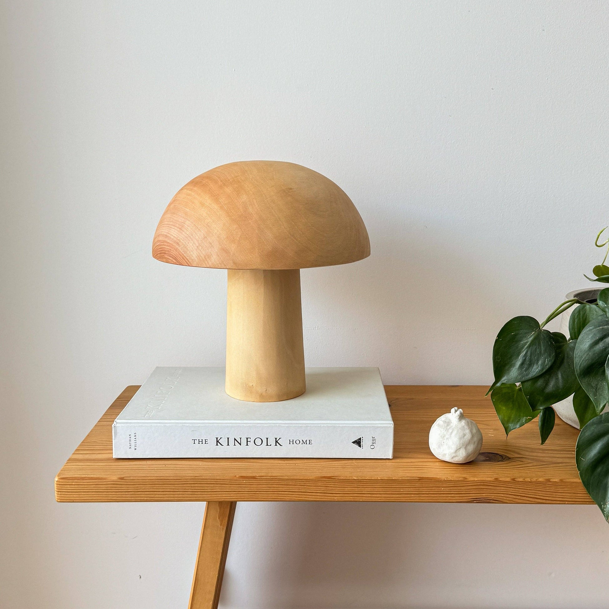 Une lampe en bois éteinte, en forme de champignon posée sur un livre.