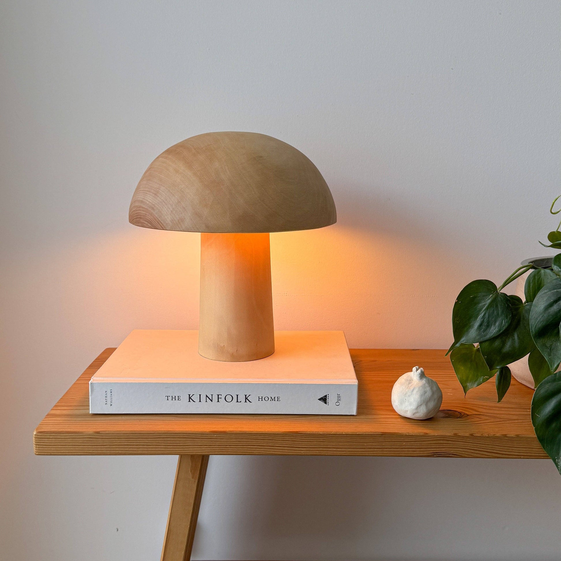 Une lampe en bois allumée, en forme de champignon posée sur un livre.
