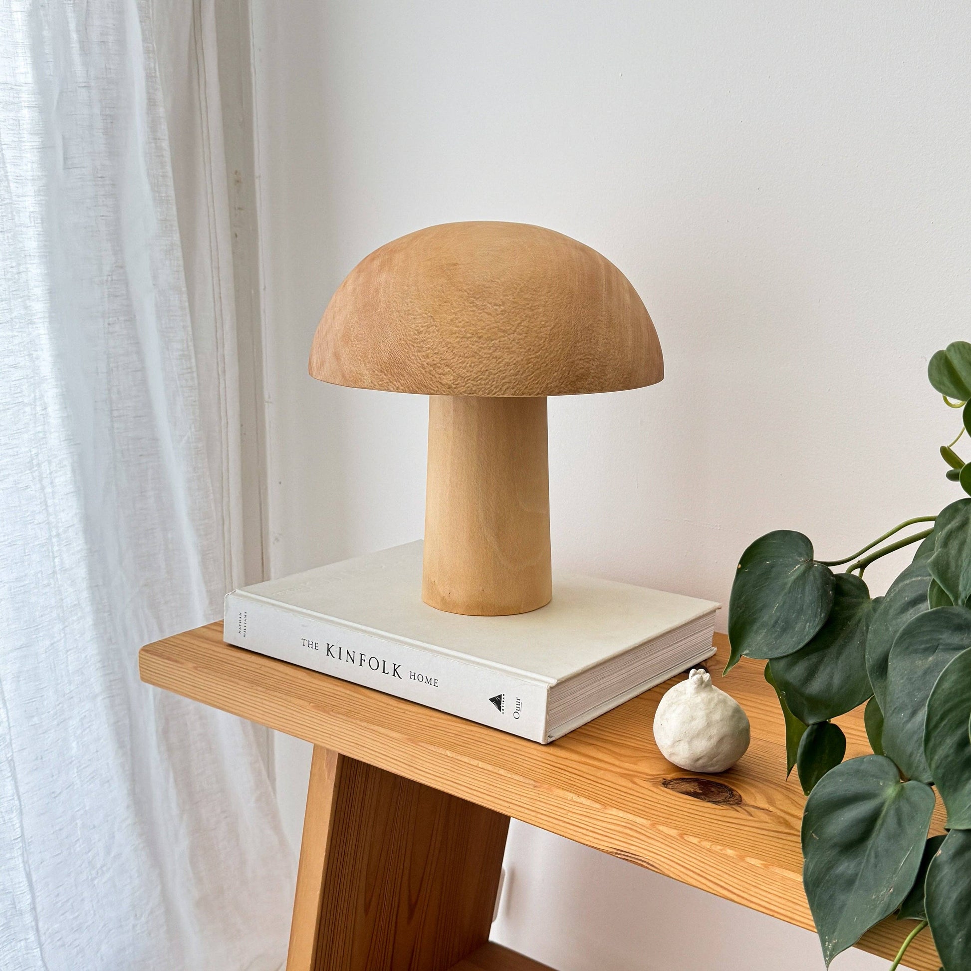 Une lampe en bois éteinte, en forme de champignon posée sur un livre.
