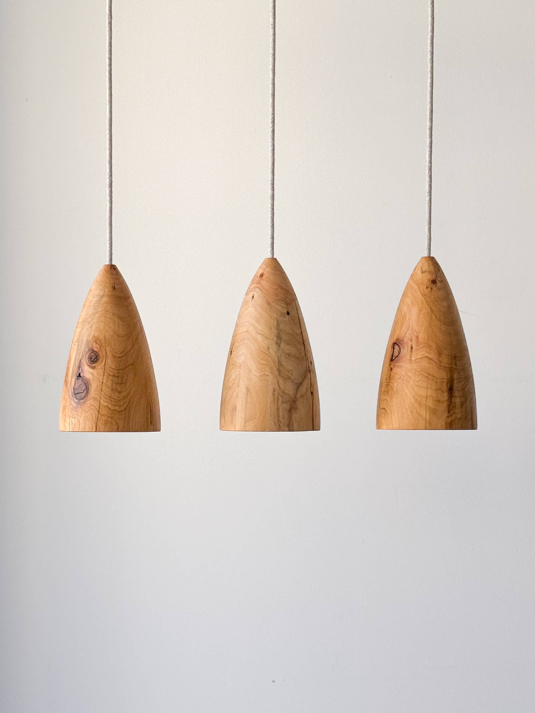 Trois lampes en bois suspendues.