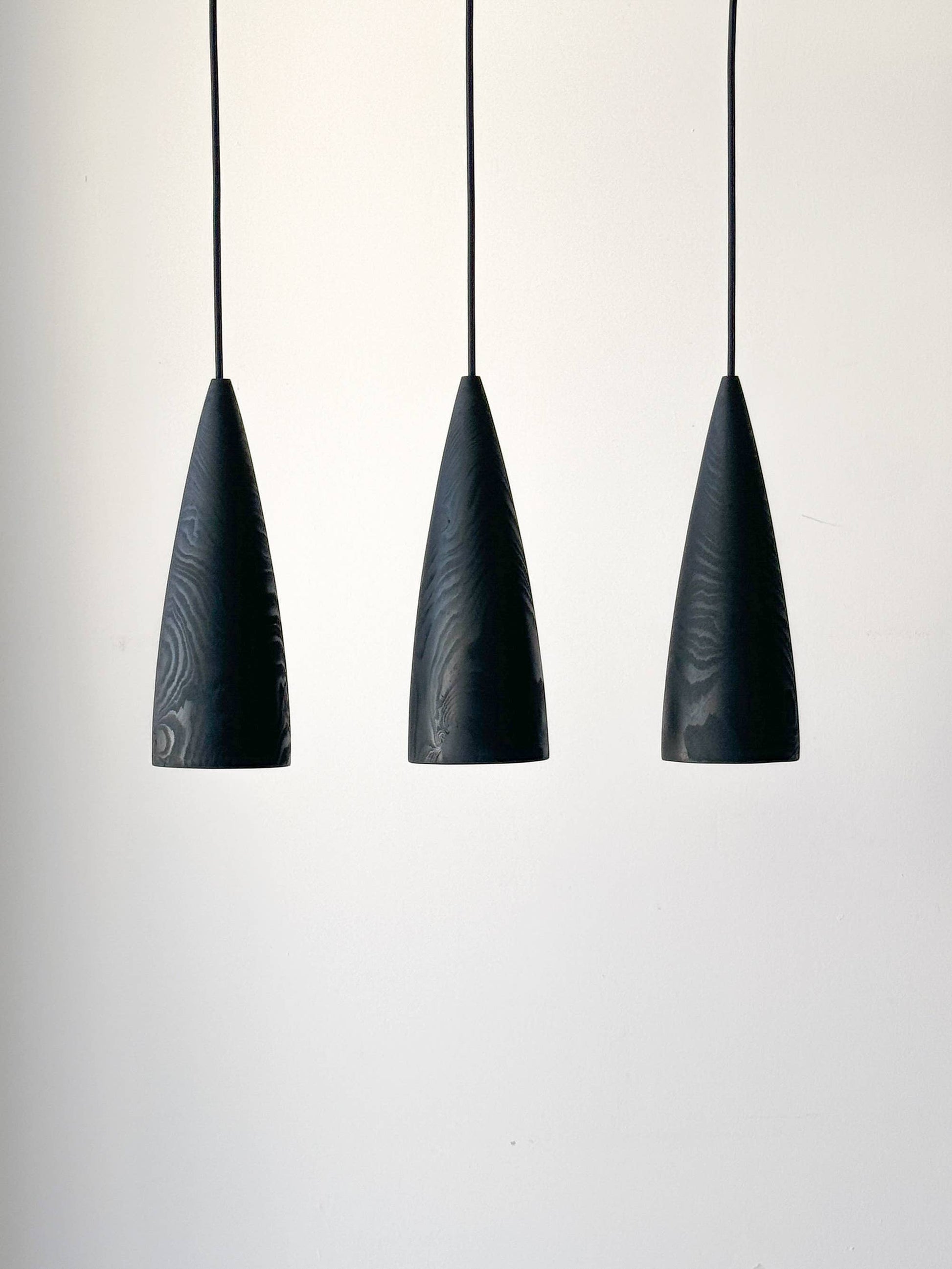 Trois lampes en bois noires suspendues.