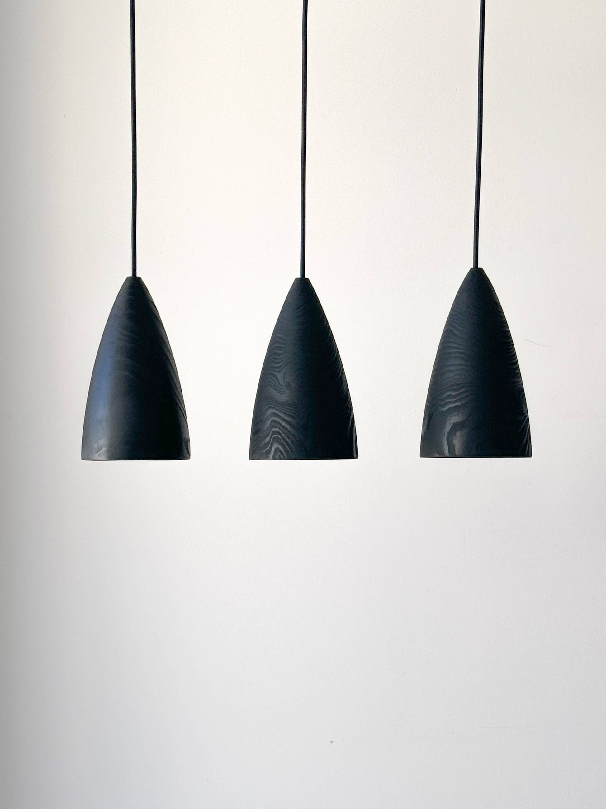 Trois lampes en bois noires suspendues.