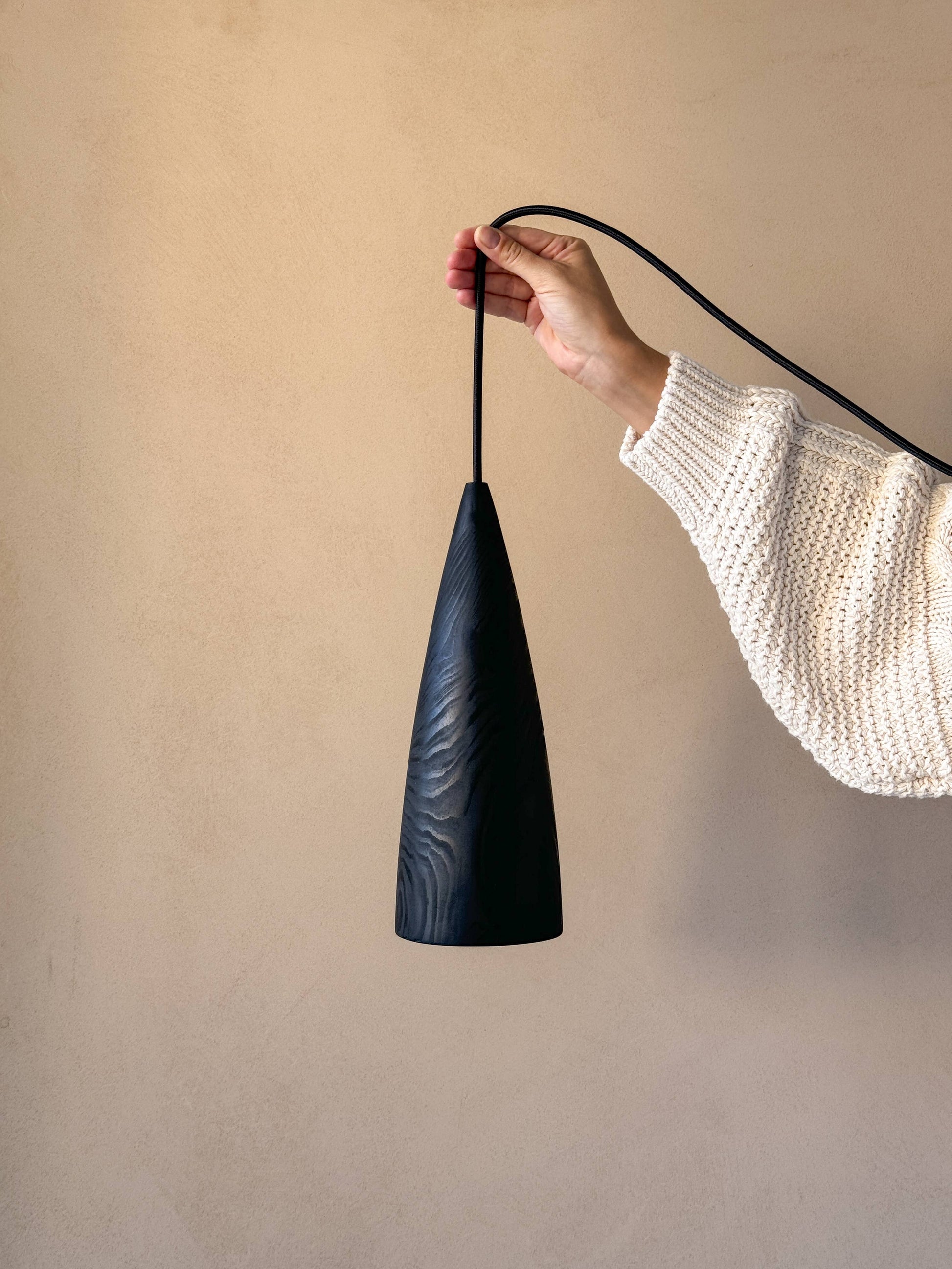 Une lampe en bois noire, tenue par une femme.