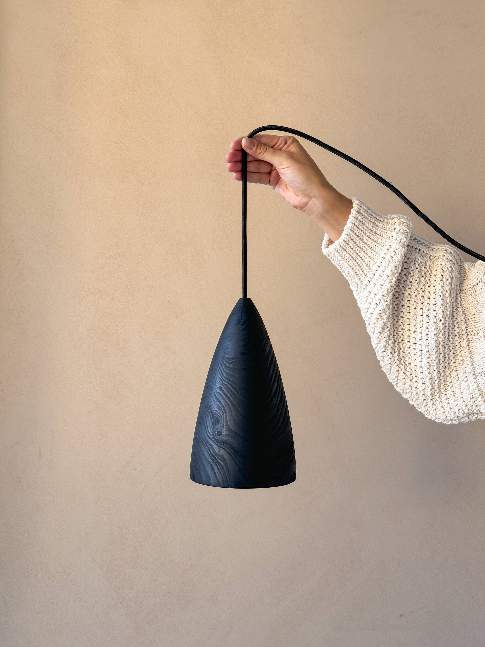 Une lampe en bois noire, tenue par une femme.