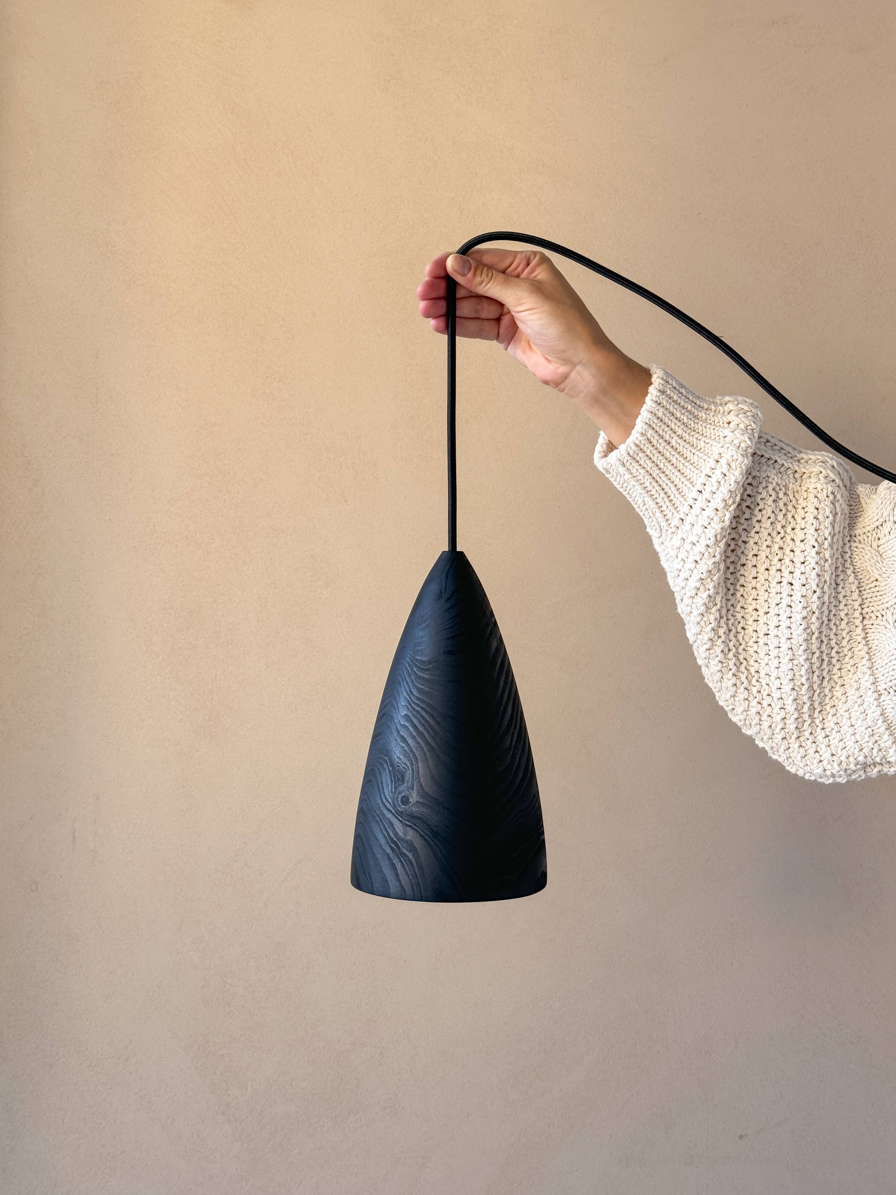 Une lampe en bois noire, tenue par une femme.