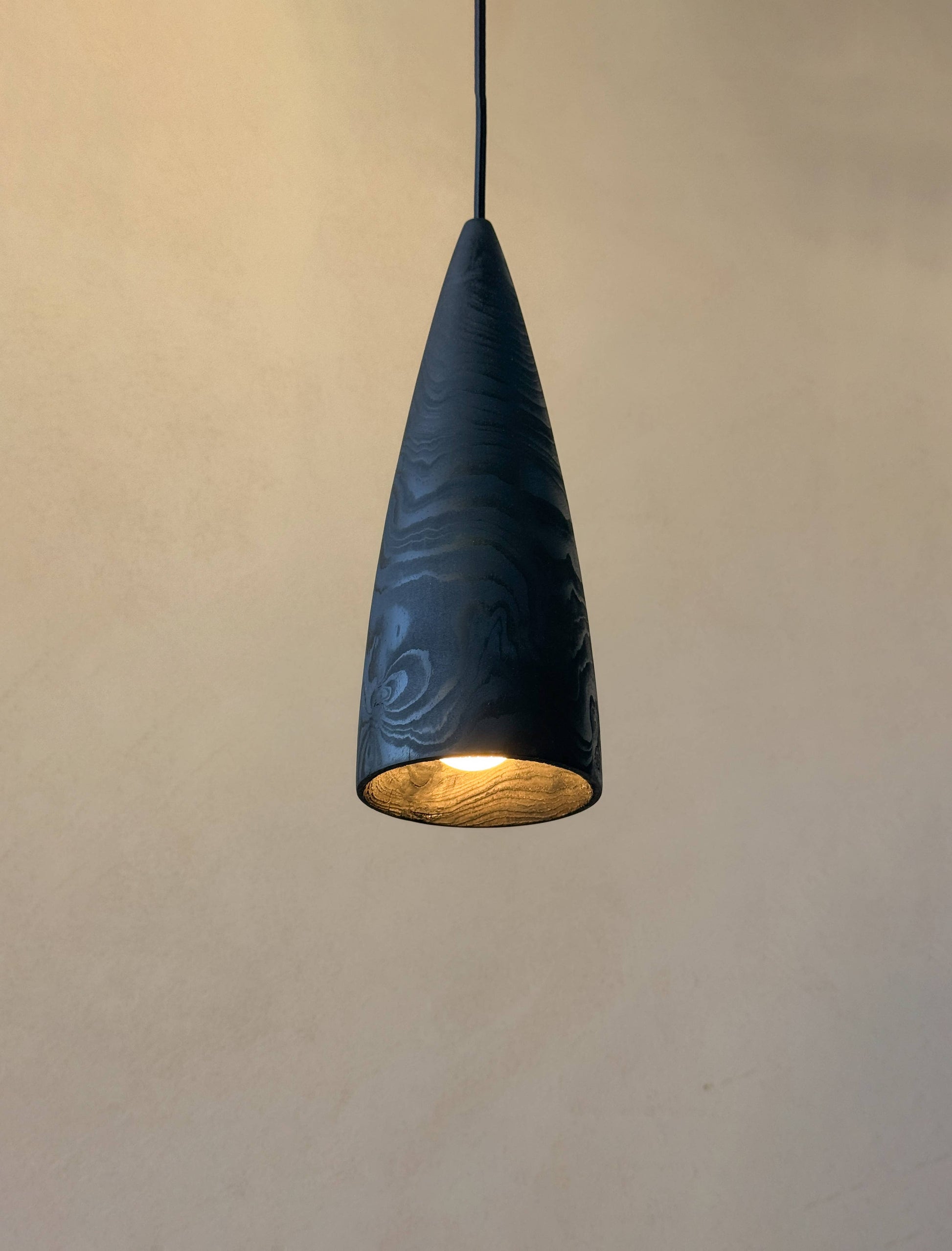 Une lampe en bois noire suspendue et allumée.