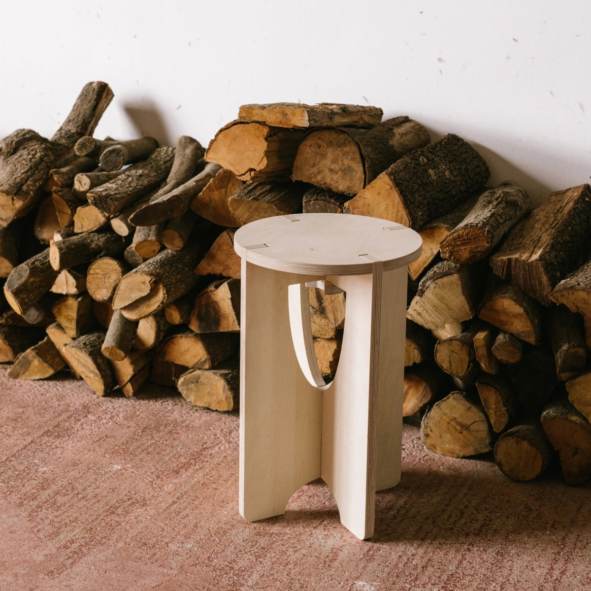 Tabouret en bois devant des troncs d'arbres coupés.
