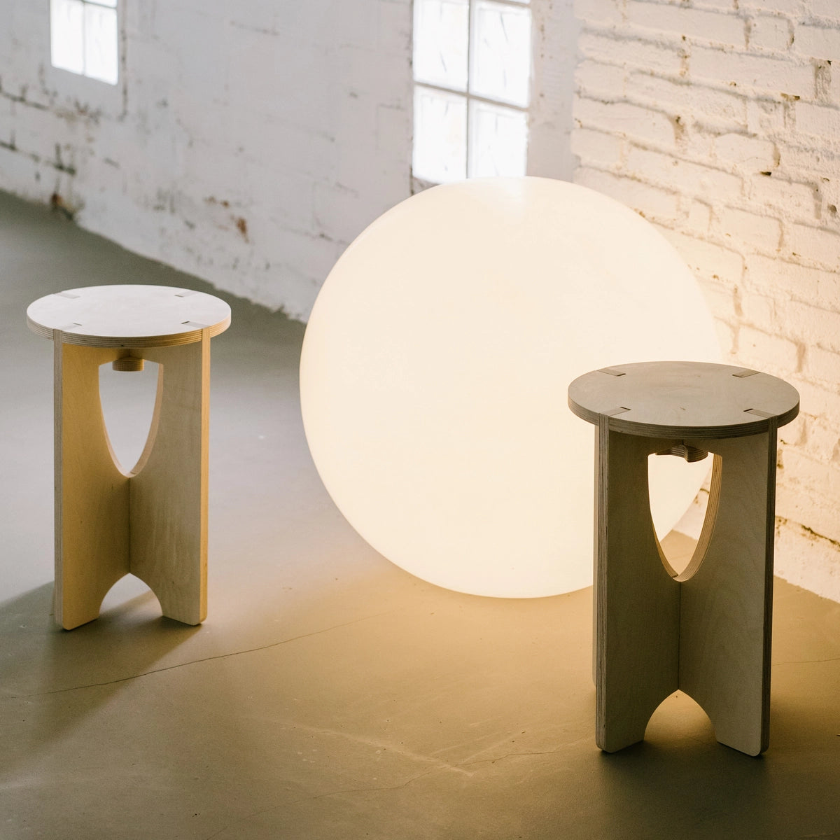 2 tabourets en bois devant une boule lumineuse.