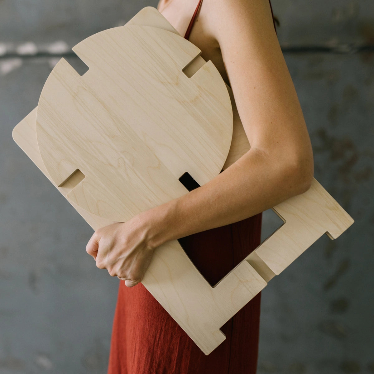 Tabouret en bois plié dans les bras d'une jeune femme.