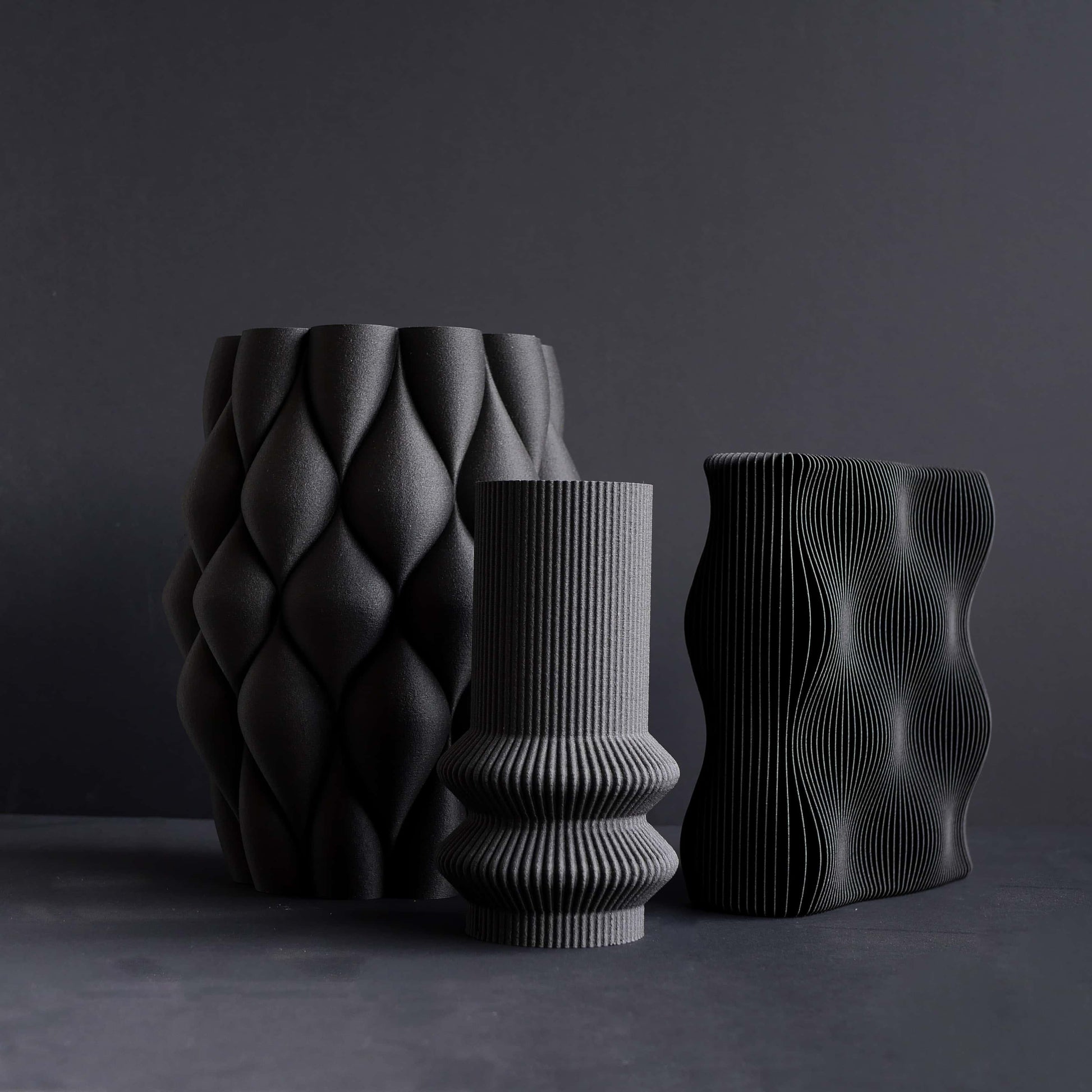 Trio de vases noirs sur fond noir.