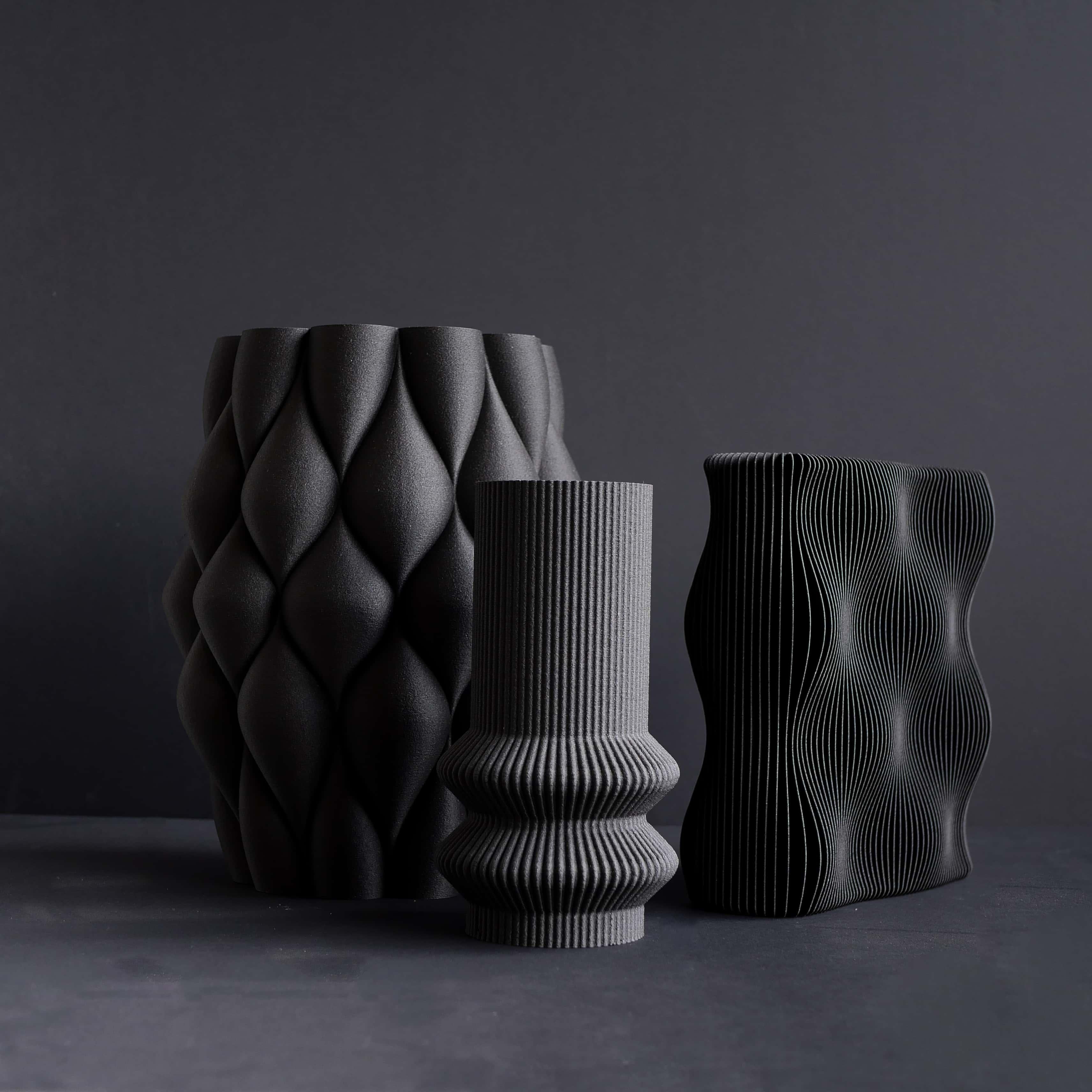 Trio de vases noirs sur fond noir.