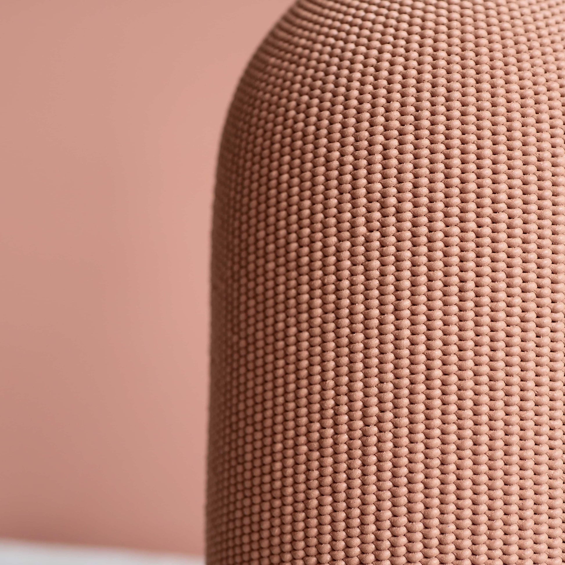 Zoom sur la matière d'un vase rose sur fond rose.