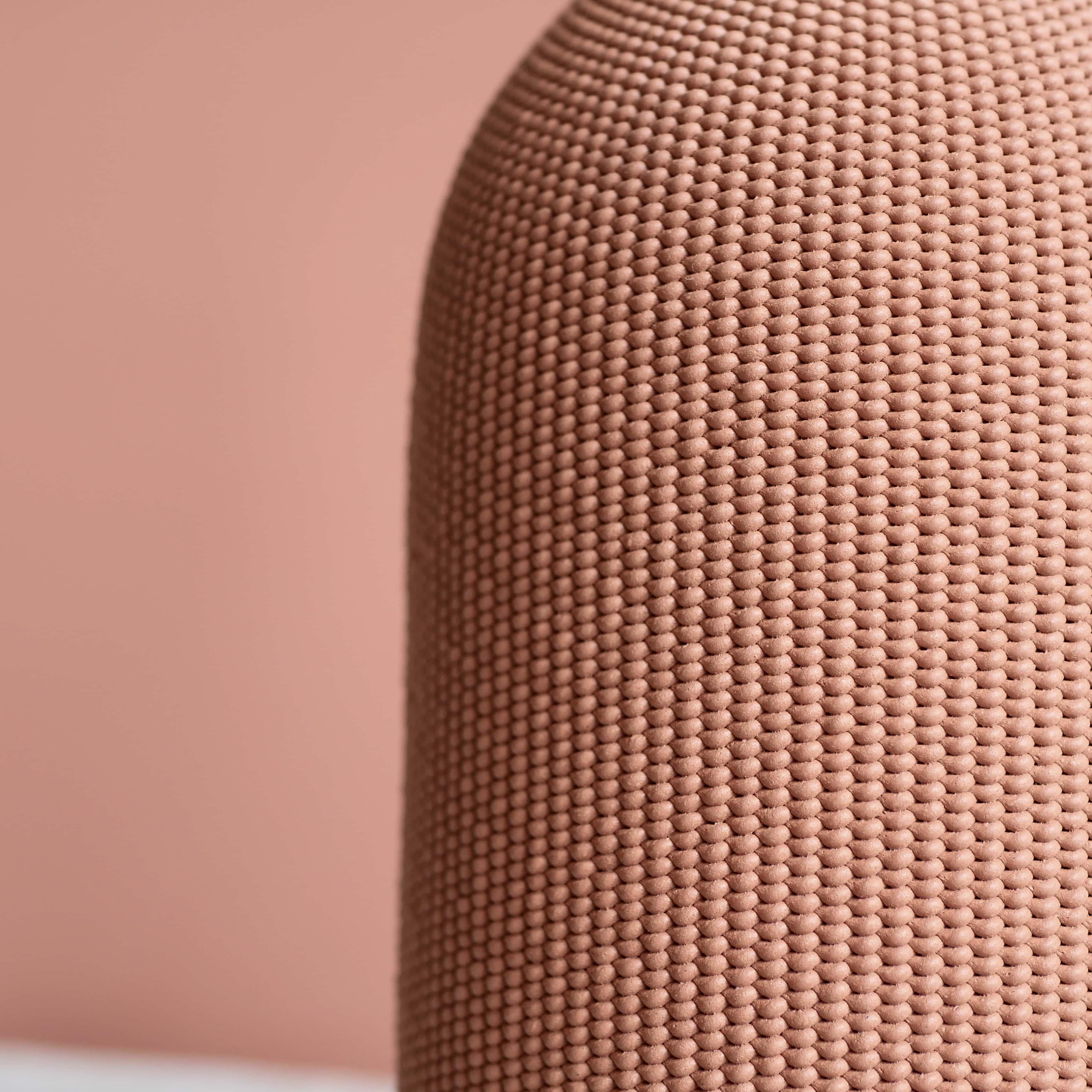 Zoom sur la matière d'un vase rose sur fond rose.