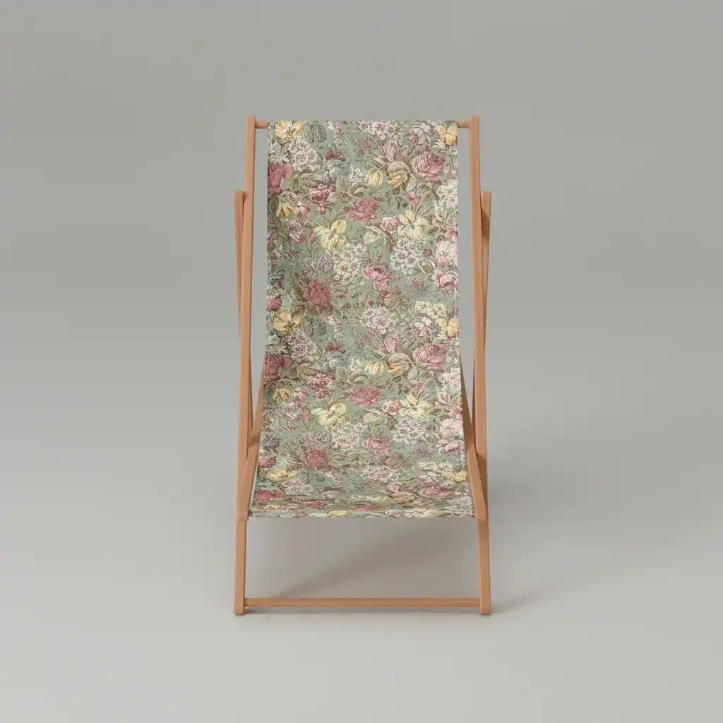 Une chaise longue en bois avec une assise en tissu à motifs floraux dans les tons vert, rose et jaune, sur un fond gris clair uni.